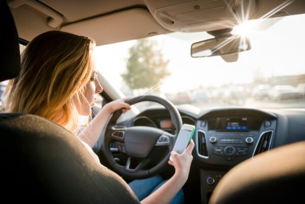 Distracted teen driver looking at phone while driving