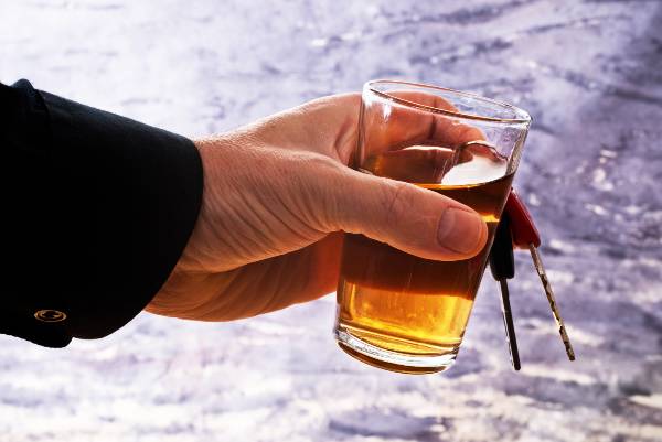 Man holding glass of alcohol and car keys