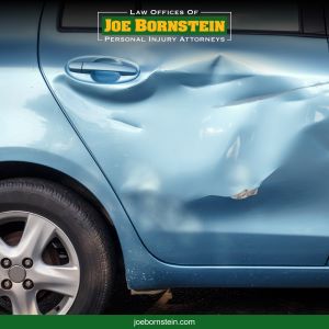 A close-up of a dented blue car door, the result of a Lewiston car accident