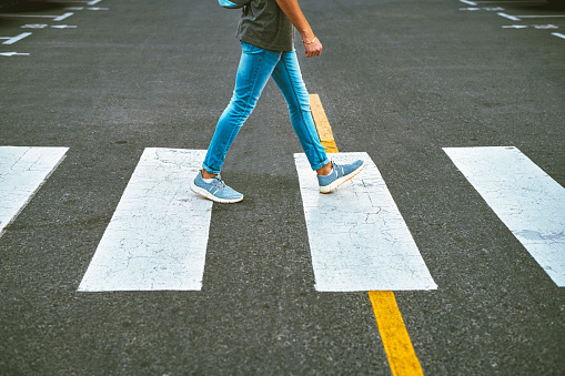 Closeup of a pedestrian using a crosswalk to cross the street.