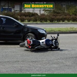 A motorcycle on its side in the road after an accident with a black car in Portland