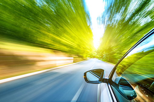 A blurry image of a car speeding down a rural road.